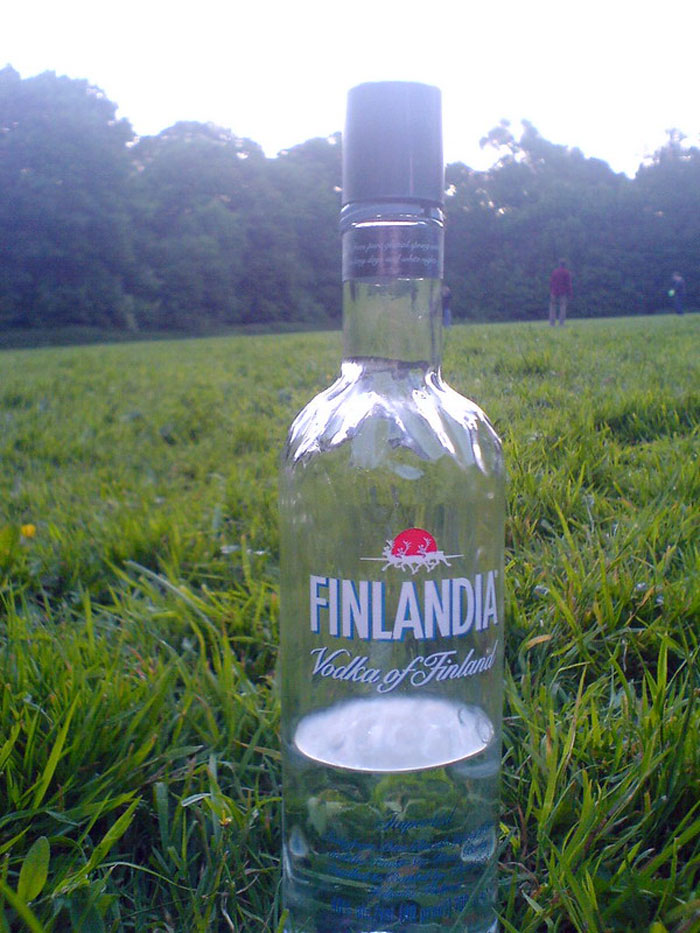 Clear Finlandia vodka bottle on grass with people in background, illustrating bartenders online group drink orders insights.