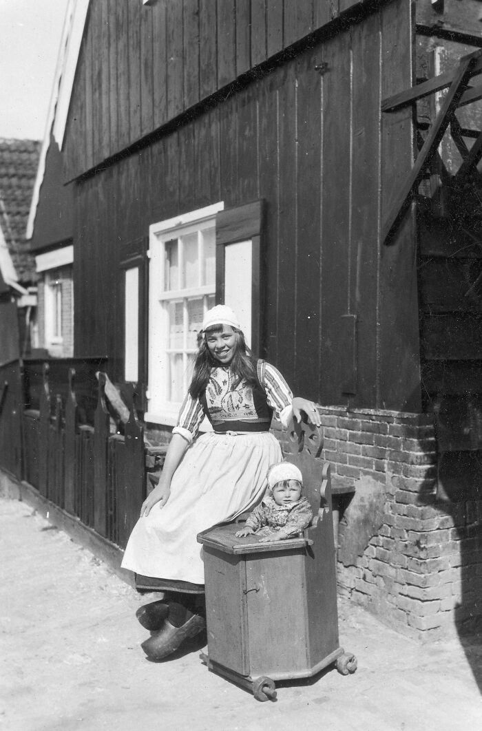 Joven madre holandesa con su bebé en un cochecito de madera. Países Bajos, 1929