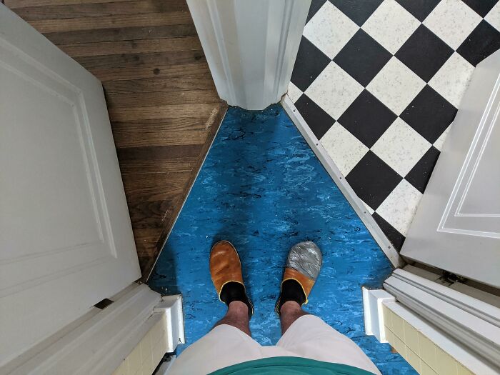 Awful interior flooring with mismatched wood, blue linoleum, and checkered tiles visible from above.