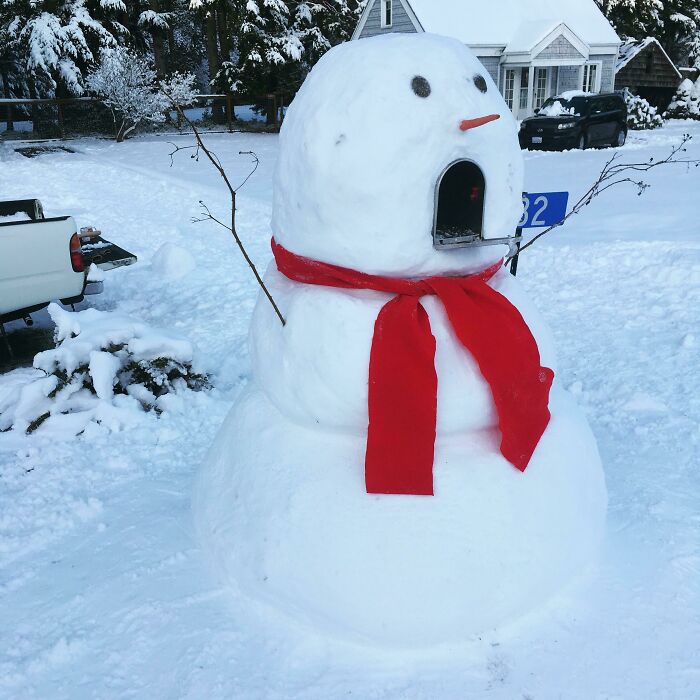 Snowman design with a red scarf and stick arms in a snowy yard featuring a unique open mouth feature.