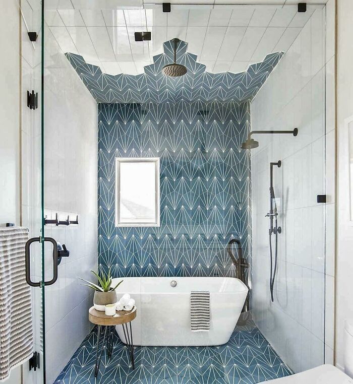 Baño con azulejos azules geométricos que suben por el techo