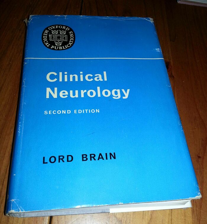 Blue cover of Clinical Neurology book by Lord Brain, a medical publication with worn edges on a wooden surface.