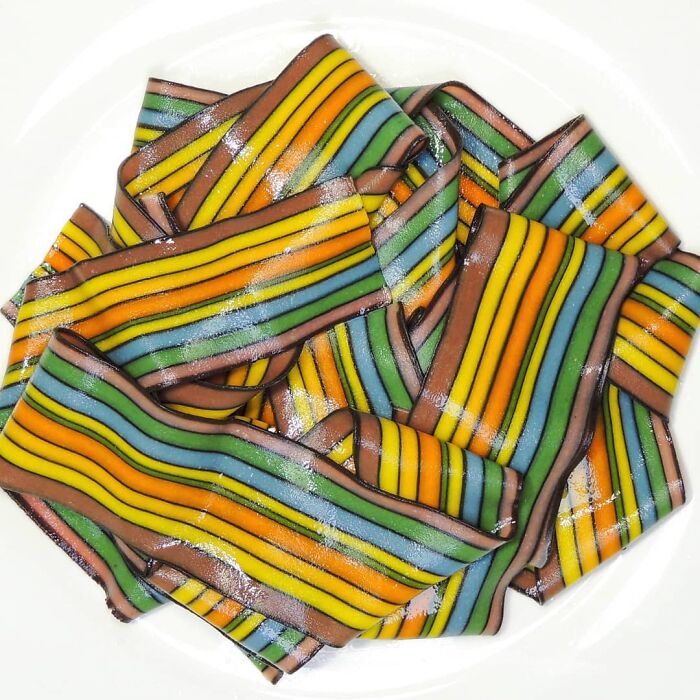 Striped colorful pasta pieces arranged on a white plate showcasing unique pasta designs by a creative chef.