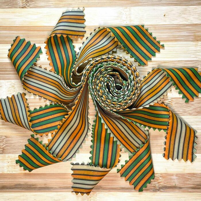 Colorful striped pasta with unique wave edges arranged in a spiral pattern showcasing creative pasta designs by a chef.