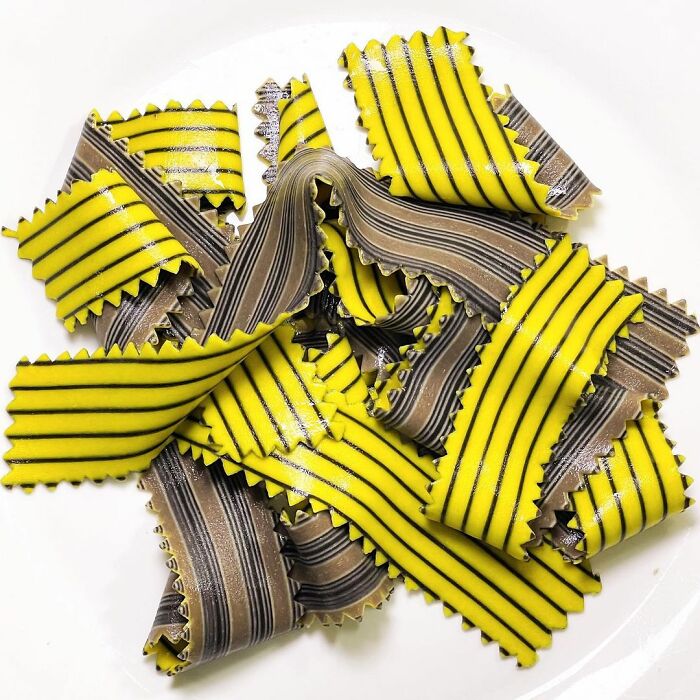 Yellow and black striped unique pasta designs by a chef, showcasing creative and viral pasta art on a white plate.