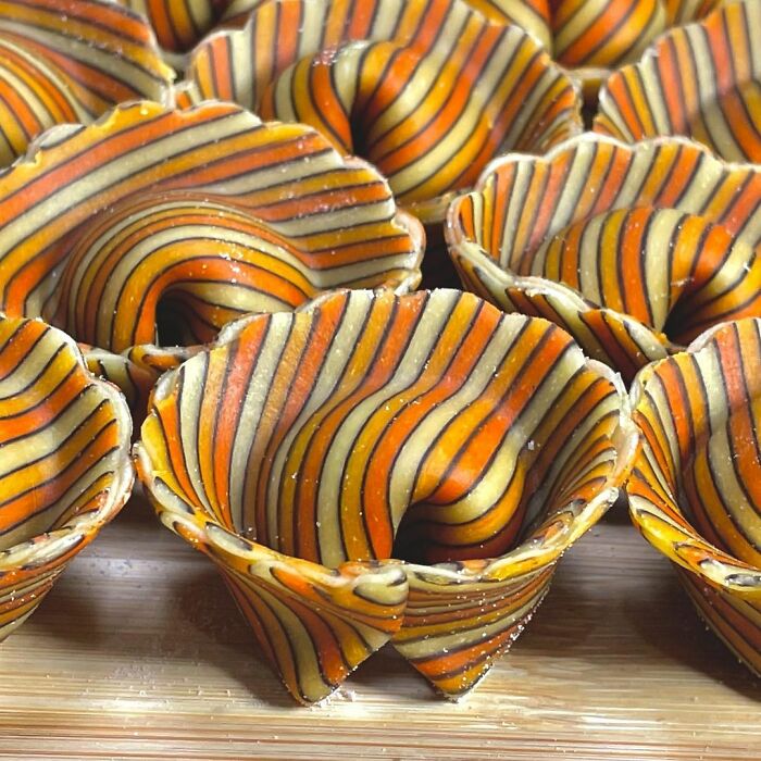 Colorful striped pasta cups with unique, artistic designs crafted by a chef, showcasing creative pasta designs trending on social media.