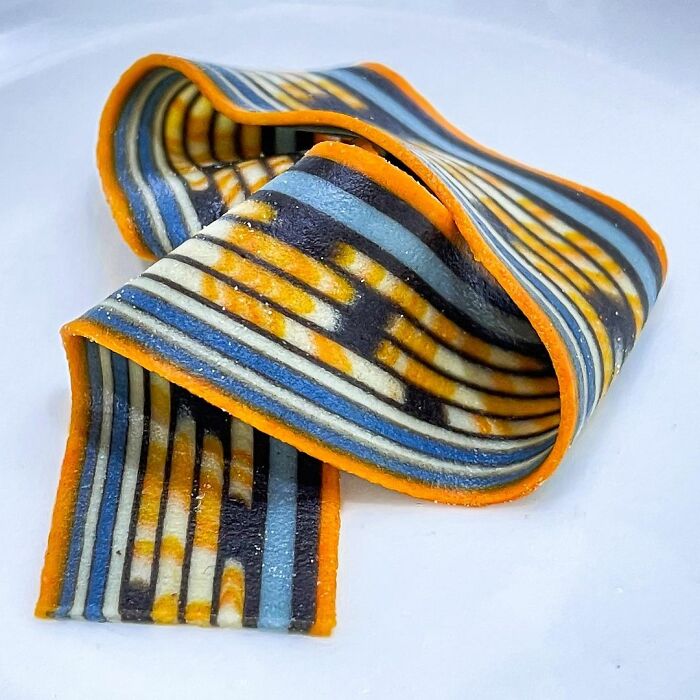 Colorful striped pasta with unique design and orange edges, showcasing creative and viral unique pasta designs by a chef.