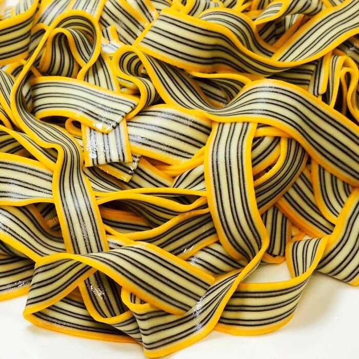 Close-up of unique pasta designs with bold black stripes and yellow edges, showcasing creative pasta art by a chef.
