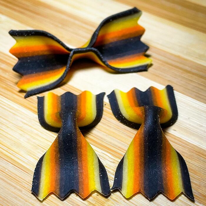 Colorful black, orange, and yellow striped pasta pieces showcasing unique pasta designs by a chef on a wooden surface