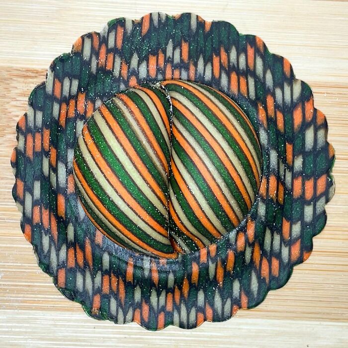Intricately striped unique pasta designs in green, orange, and cream colors displayed on a patterned surface.