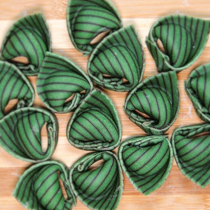 Unique green striped pasta designs arranged on a wooden surface showcasing creative pasta artistry by a skilled chef.