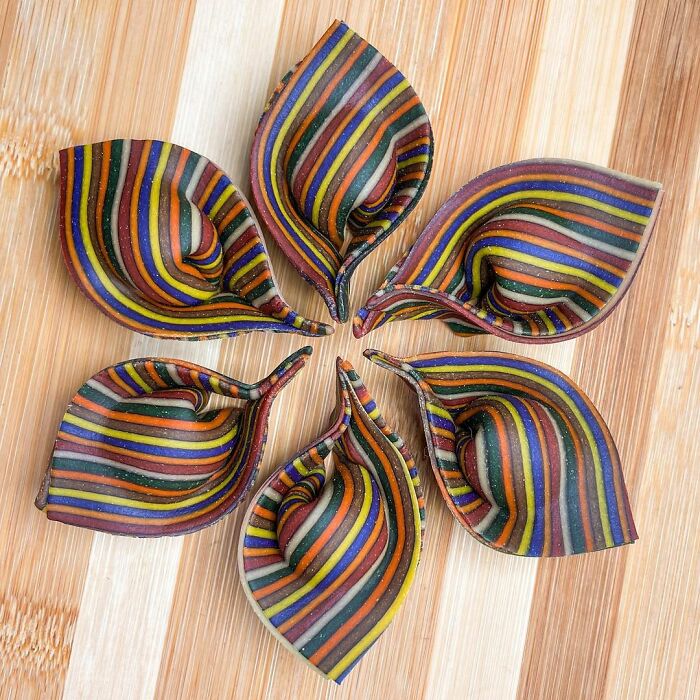 Colorful striped pasta designs arranged in a circular pattern on a wooden surface, showcasing unique pasta creativity.