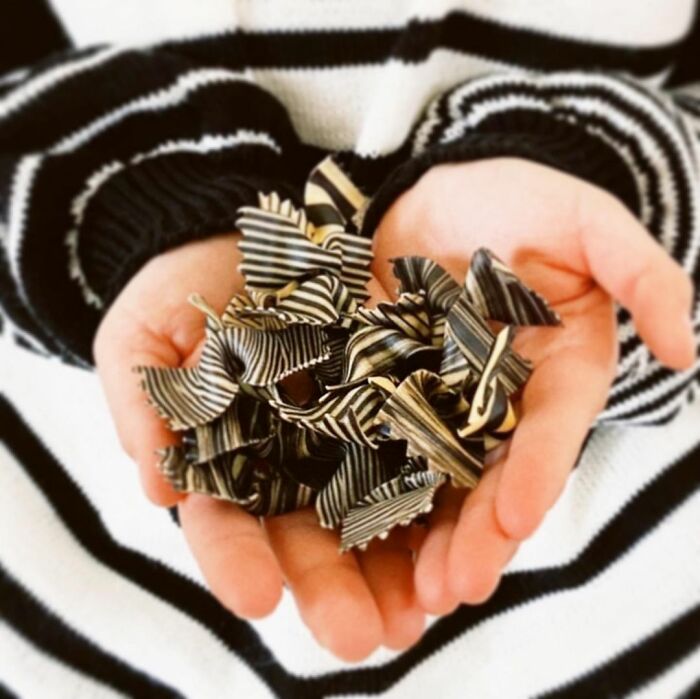 Hands holding unique striped pasta designs by a chef, showcasing creative and viral pasta art on social media.