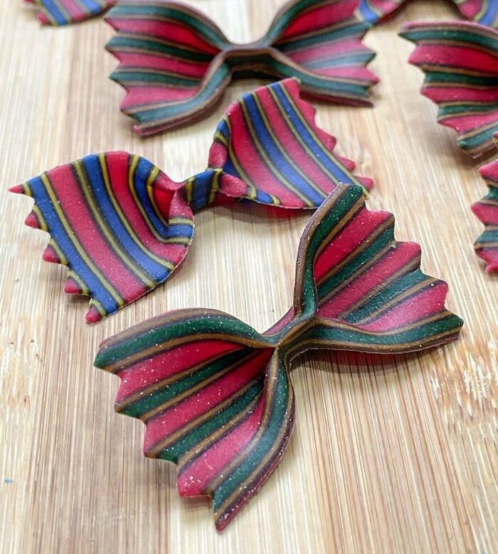 Colorful striped bowtie pasta design made by a chef showcasing unique pasta creativity on a wooden surface.