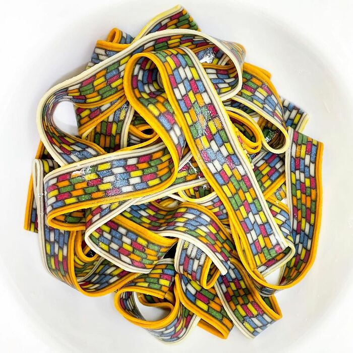 Colorful unique pasta designs by a chef arranged in a bowl, showcasing intricate and vibrant patterns on the noodles.
