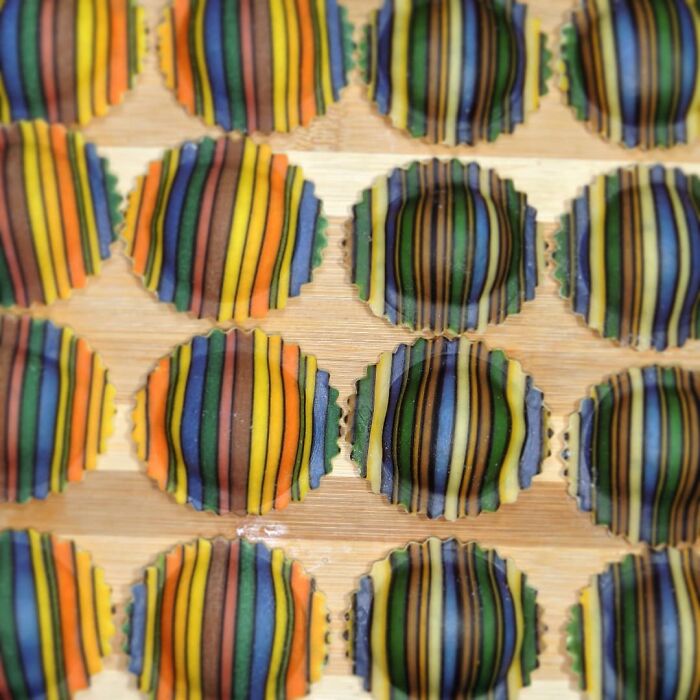 Colorful striped ravioli arranged on a wooden board showcasing unique pasta designs by a creative chef.