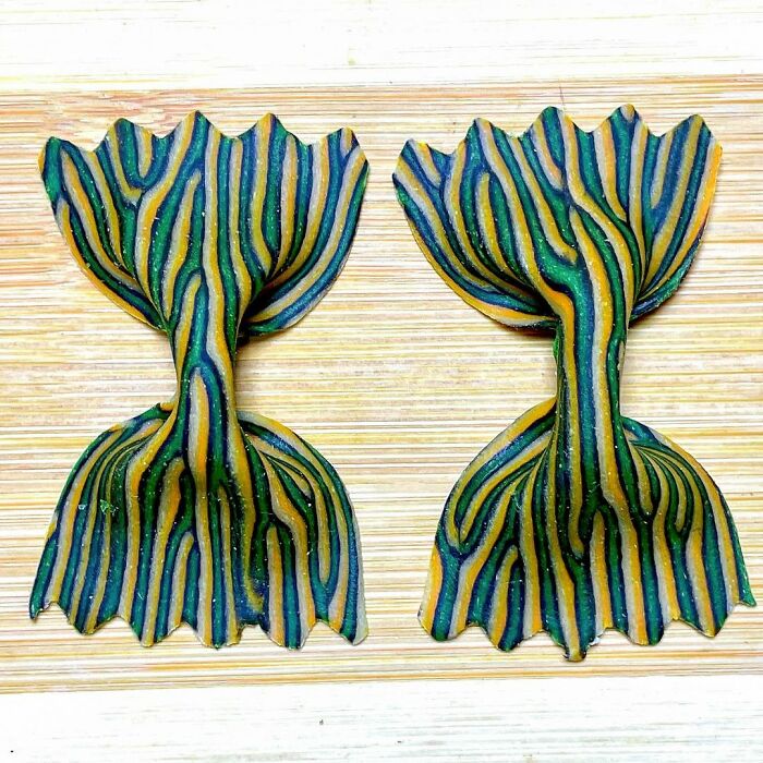 Two pieces of unique pasta designs with colorful striped patterns placed on a wooden surface.