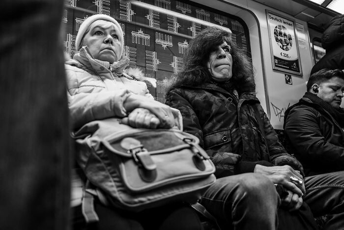 Black and white street photo of diverse passengers sitting on public transit, capturing powerful everyday urban moments.
