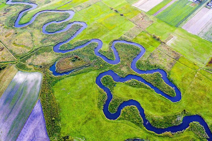 Aerial view of Poland’s winding river and diverse green farmland showcasing modern and interesting landscapes.