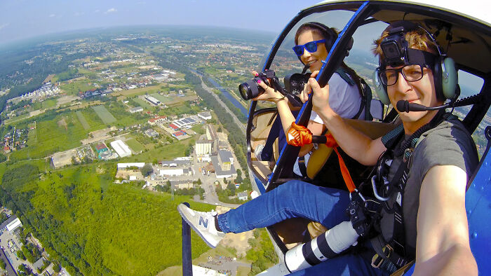 Two photographers in a helicopter capturing aerial pictures of Poland’s modern, interesting, and diverse landscape.