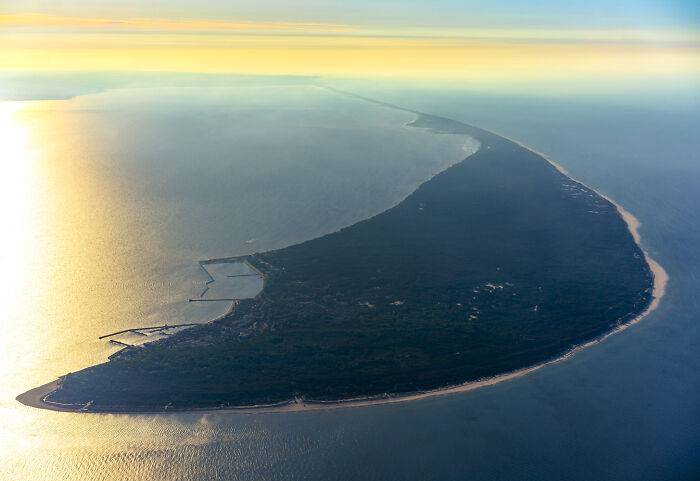 Aerial view of a modern and diverse coastal area in Poland showing natural landscape and shoreline at sunset.