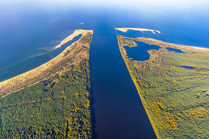 Aerial view of Poland showing modern and diverse landscapes with water, forests, and sandy shores under clear skies