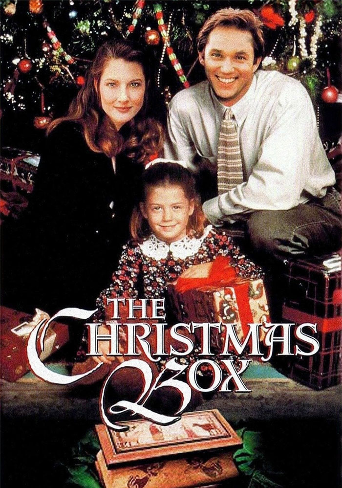 "Family posing in front of a Christmas tree with gifts; 'The Christmas Box' movie poster."