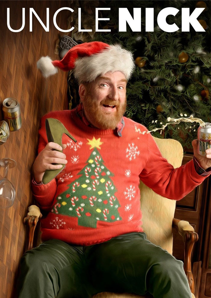 Man in Santa hat with Christmas sweater, sitting by a decorated tree, representing best Christmas movies vibe.