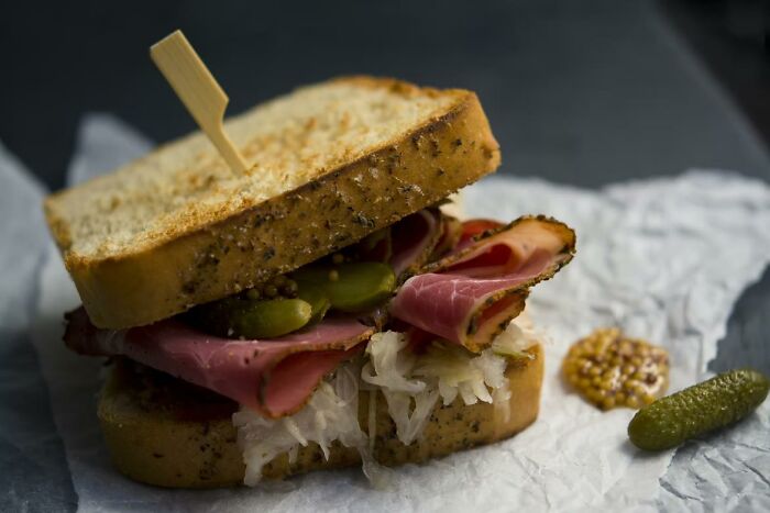 Close-up of a deli sandwich with pickles and mustard, illustrating encounters that made people think about stupidity.