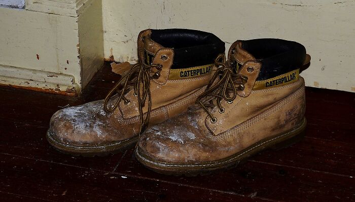 Worn Caterpillar boots on wooden floor symbolizing the moment that made men decide on divorce emotions.