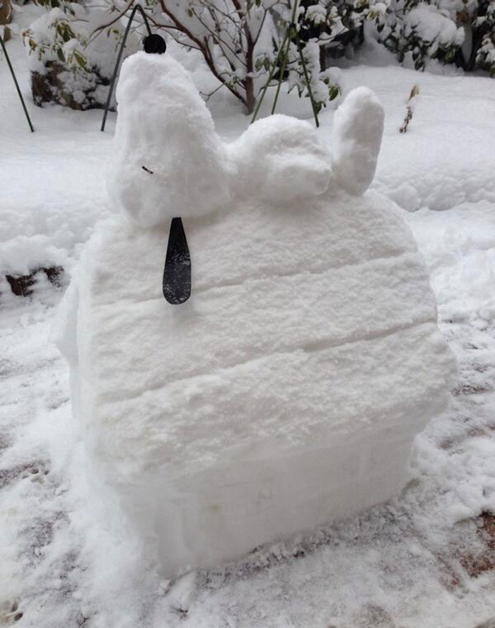 Snowman design shaped like a dog lying on a snow-covered doghouse with detailed ears and nose.