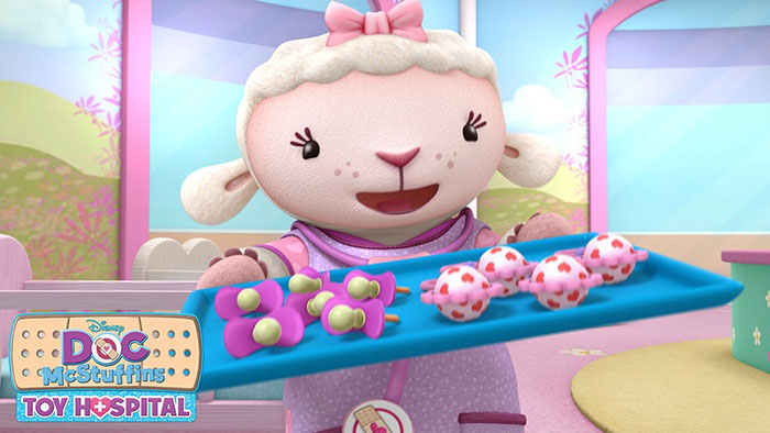 Cute animated character in a toy hospital setting holding a tray with colorful medical items, smiling happily.