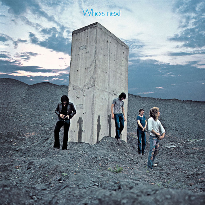 Iconic album cover featuring band members standing by a concrete structure at dusk.