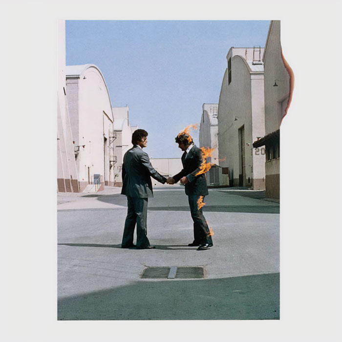 Two men in suits shake hands on a classic album cover, one engulfed in flames.