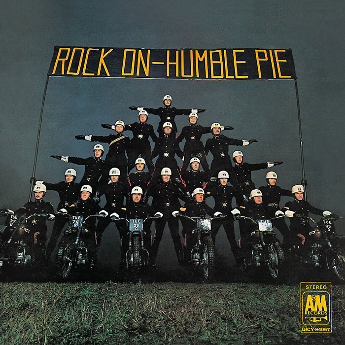 Group of police officers forming a pyramid on motorcycles under "Rock On-Humble Pie" sign, featuring classic album cover.
