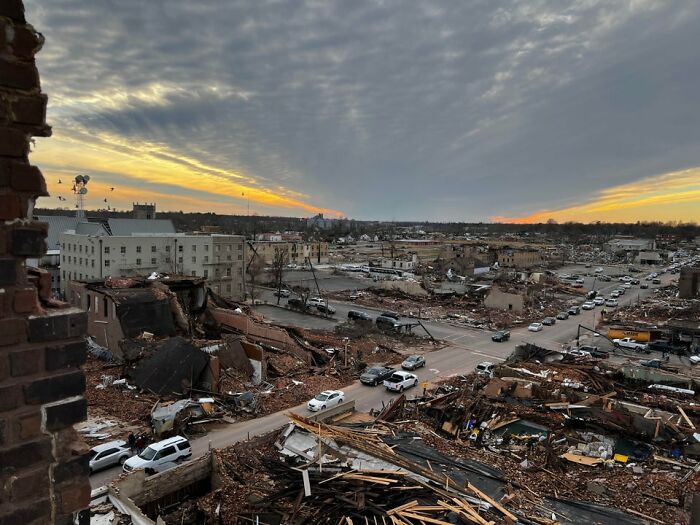 View of Mayfield tornado aftermath showing extensive destruction of buildings and debris under a dramatic cloudy sky at sunset View of Mayfield tornado aftermath showing extensive destruction of buildings and debris under a dramatic cloudy sky at sunset