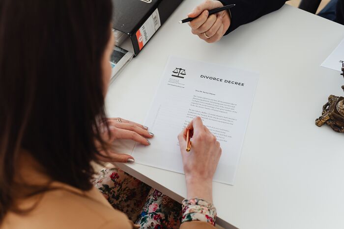 Woman signing a divorce decree at a desk, illustrating a date that took a disturbing and simply wrong turn.