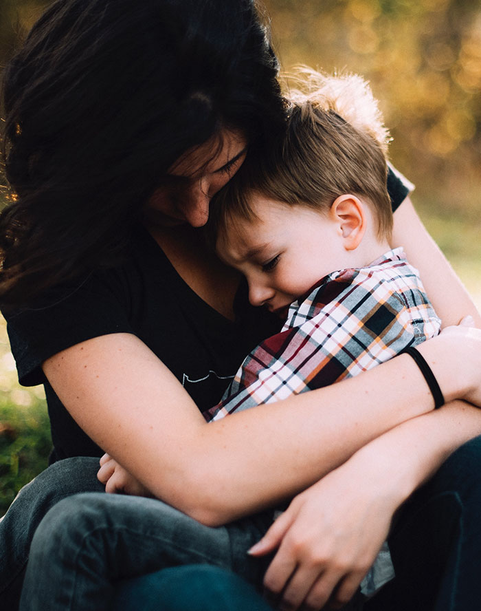Woman hugging boy on her lap