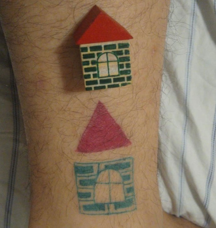 Tattoo of geometric house design with a triangular roof on a person's skin, showcasing unique artistic style.