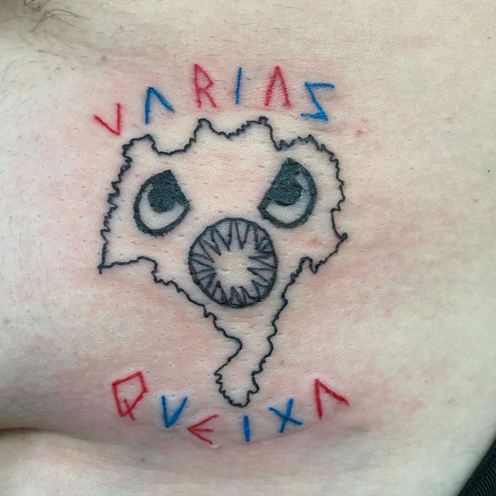 Unique tattoo design with abstract face and text in bold colors, exemplifying artist's unconventional style.