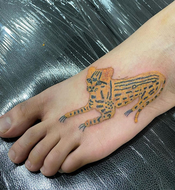 Unique tattoo design of a stylized cat on a foot by a tattoo artist known for her distinct style.
