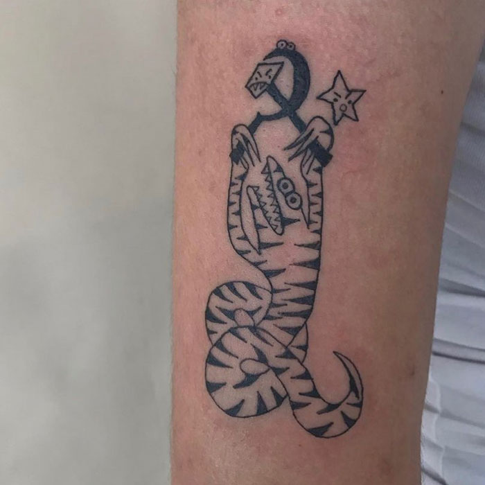 Abstract tattoo design by an artist known for unique styles, featuring a playful snake and star on forearm.