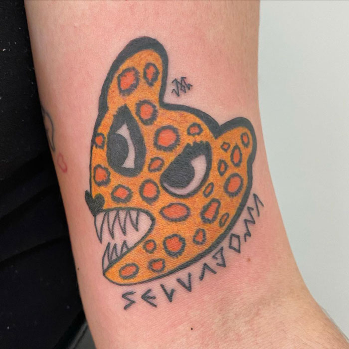 Unique tattoo design of an abstract leopard head with bold lines and orange spots.