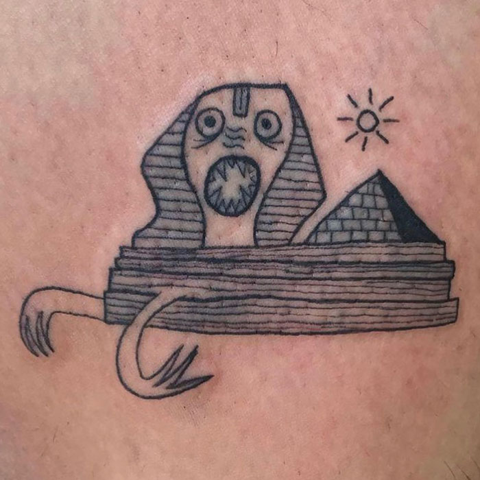 Creative tattoo with abstract sphinx, pyramid and sun design, showcasing unique style of tattoo artist known for not drawing well.