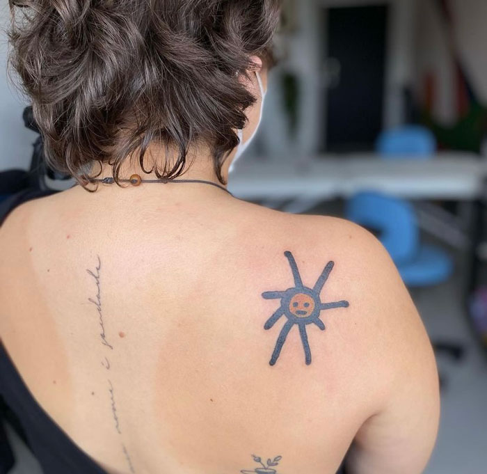 Back tattoo of a simplistic sun design by a tattoo artist known for unique, unpolished drawings.
