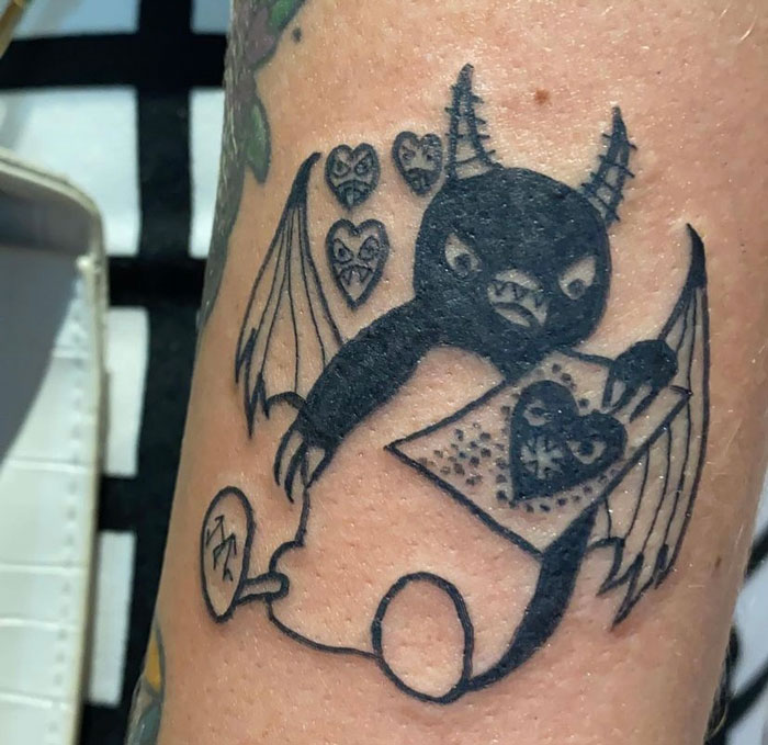 Tattoo of a quirky bat drawing hearts, highlighting a unique artist's style appreciated for its raw simplicity.