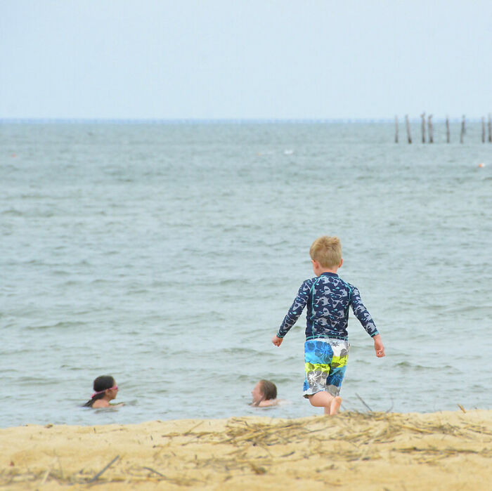Young boy in swimwear walking on beach near water, symbolizing what horrid secrets parents might be unaware of.