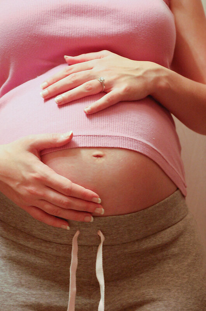 Close-up of pregnant woman holding belly, illustrating secrets parents may be unaware of regarding pregnancy.