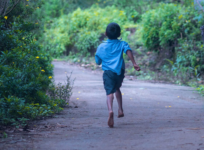 Child running barefoot on a forest path, symbolizing secrets parents keep unaware to their children.