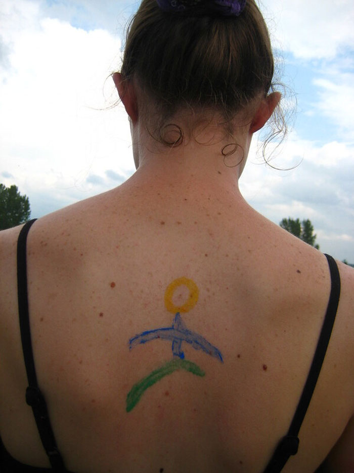 Woman with a simple colorful drawing on her upper back under a cloudy sky, exploring secrets and awareness about parents.